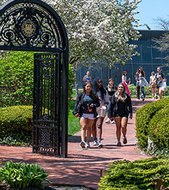    Students walk near the archway at Bryant University.
