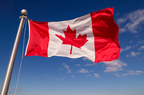 The Canadian flag flies against a blue sky.