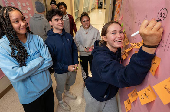 Nia Scott, Cameron Juliano, Iyana Braswell, and Peyton Bosshardt brainstorm outside of a Unistructure classroom during IDEA, Bryant's formative design thinking program for first-year students.