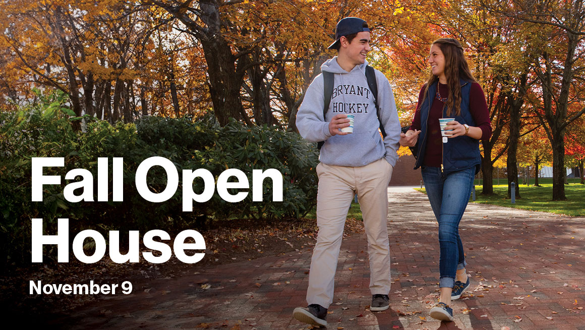 Two Bryant students walk along a path with fall foliage.